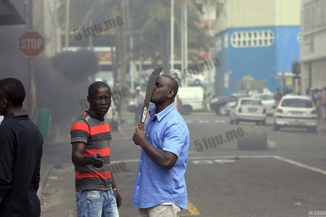 图为当地排外抗议者与警察发生冲突，一名外国人骚乱中手持长刀以保护自己。